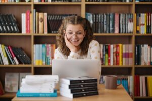 Girl studying among books using laptop